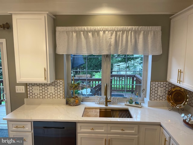 kitchen featuring light stone counters, a sink, white cabinets, dishwasher, and tasteful backsplash