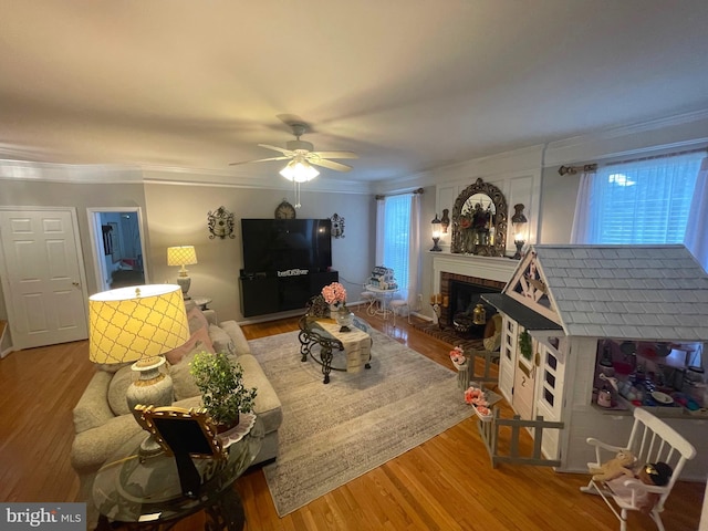 living area featuring a wealth of natural light, ornamental molding, a brick fireplace, and wood finished floors