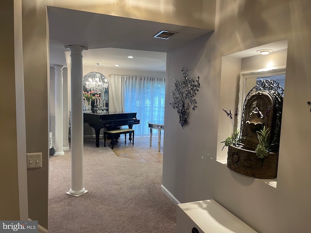 corridor featuring visible vents, a notable chandelier, carpet, decorative columns, and baseboards