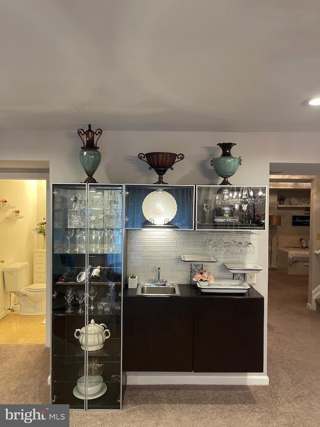 bar featuring a sink, indoor wet bar, decorative backsplash, and carpet flooring