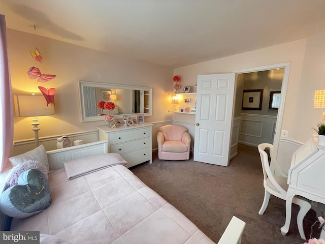 bedroom with wainscoting, dark carpet, and a decorative wall