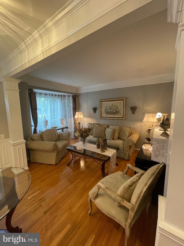 living area featuring hardwood / wood-style floors, ornamental molding, and ornate columns