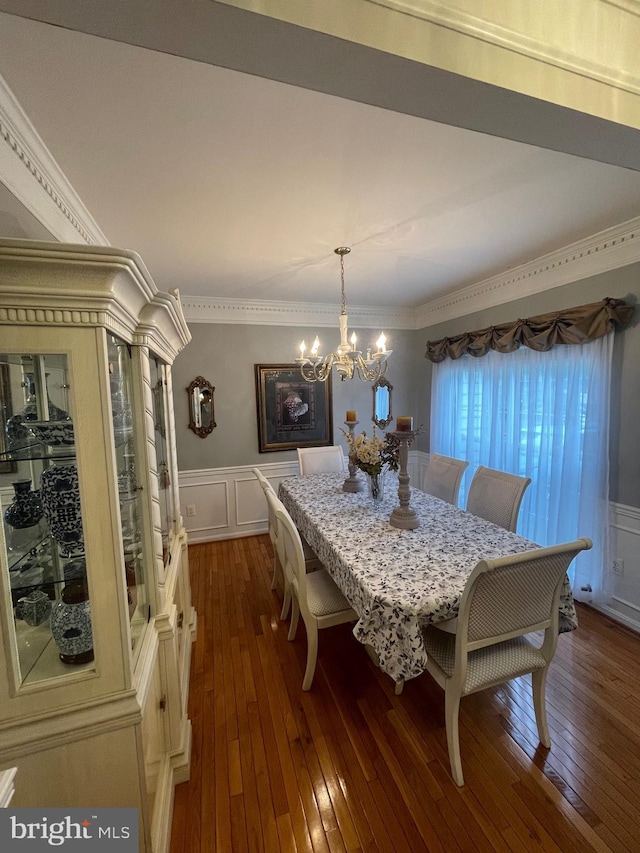 dining area featuring wainscoting, dark wood finished floors, crown molding, and a decorative wall