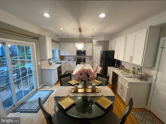 kitchen with a sink, light wood-type flooring, black appliances, and light countertops