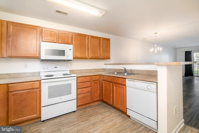 kitchen featuring an inviting chandelier, light hardwood / wood-style flooring, white appliances, sink, and pendant lighting