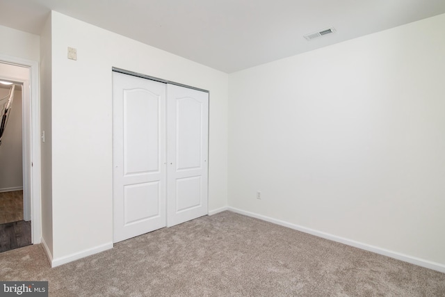 unfurnished bedroom featuring light carpet and a closet