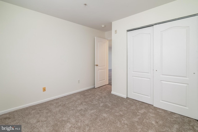 unfurnished bedroom featuring light colored carpet and a closet