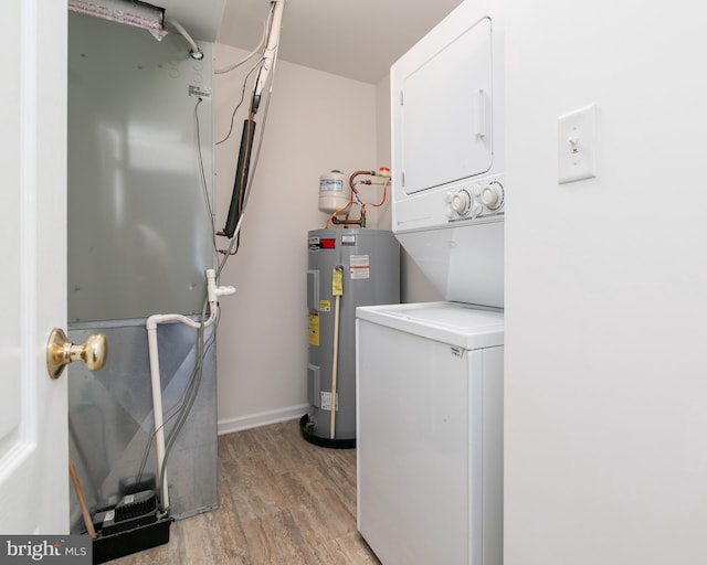 laundry area with electric water heater, stacked washer and dryer, and light hardwood / wood-style floors