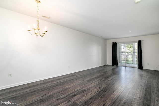 empty room with dark hardwood / wood-style floors and a notable chandelier