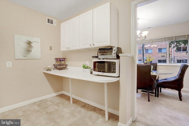 kitchen featuring an inviting chandelier and white cabinetry