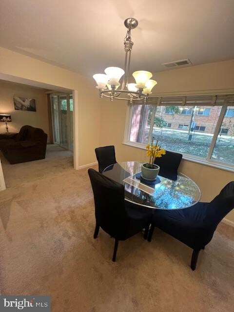 carpeted dining space featuring an inviting chandelier