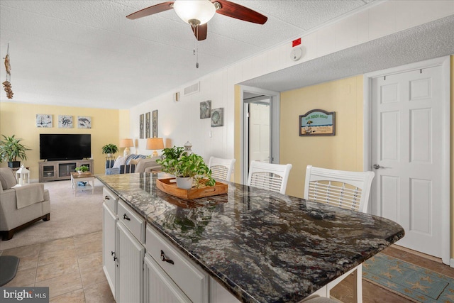 kitchen featuring white cabinets, ceiling fan, a kitchen island, and a breakfast bar area