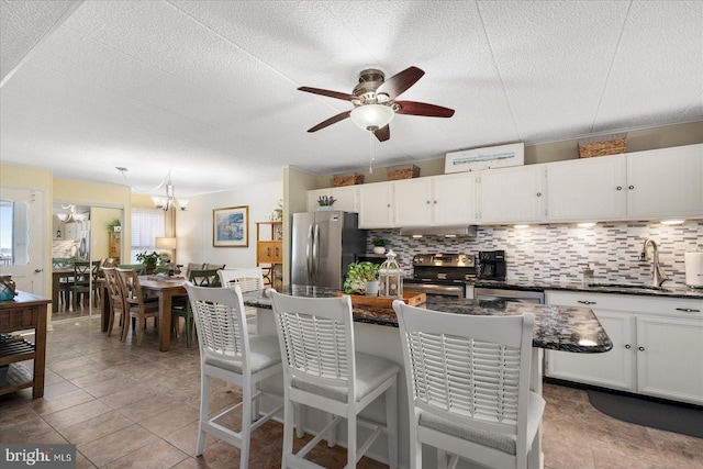 kitchen featuring stainless steel appliances, sink, ceiling fan with notable chandelier, and white cabinetry