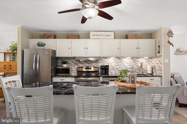 kitchen featuring range hood, white cabinets, ceiling fan, and stainless steel appliances