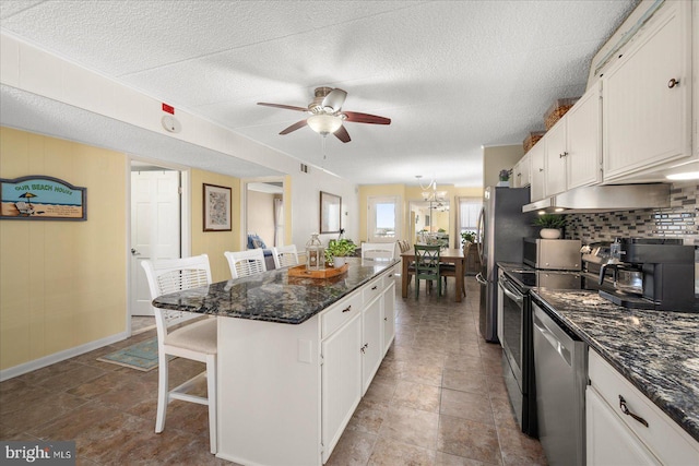 kitchen with ceiling fan with notable chandelier, white cabinetry, a kitchen bar, a kitchen island, and appliances with stainless steel finishes