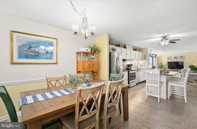 tiled dining space with ceiling fan with notable chandelier and a textured ceiling