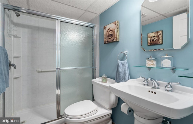 bathroom with a paneled ceiling, toilet, sink, and an enclosed shower