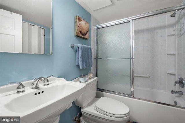 full bathroom featuring toilet, combined bath / shower with glass door, and sink