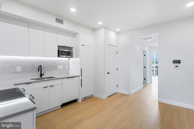 kitchen featuring light wood-type flooring, white cabinetry, sink, and dishwasher