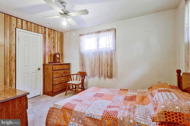 bedroom featuring light carpet, ceiling fan, and wooden walls