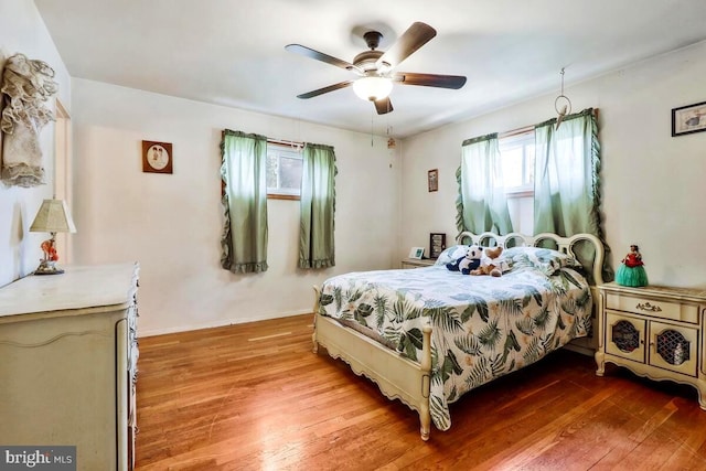 bedroom featuring ceiling fan, wood-type flooring, and multiple windows