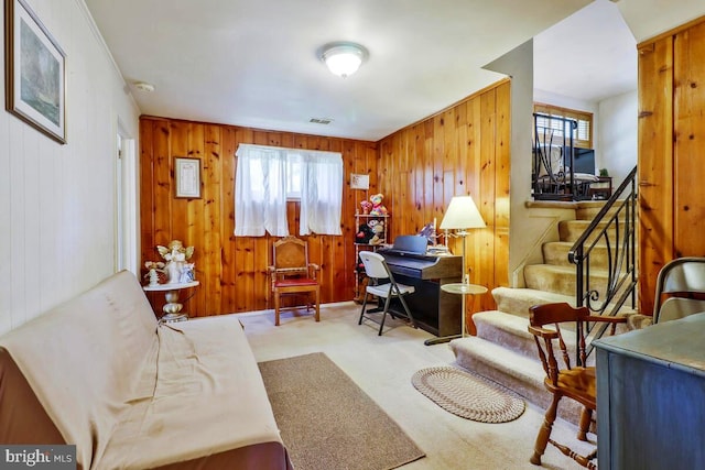 living area with crown molding, wood walls, and carpet floors