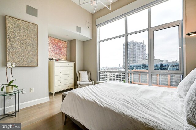 bedroom with a towering ceiling and light hardwood / wood-style flooring