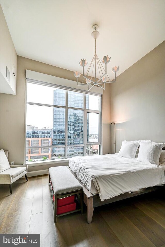 bedroom featuring a notable chandelier, wood-type flooring, and multiple windows