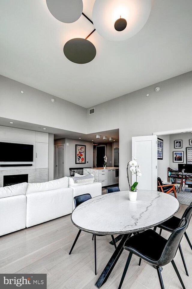 dining area with a towering ceiling and light hardwood / wood-style floors