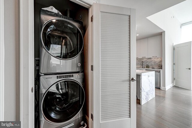 laundry area featuring stacked washer and dryer and hardwood / wood-style floors