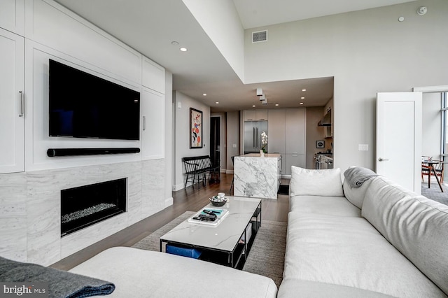 living room with a towering ceiling and dark wood-type flooring