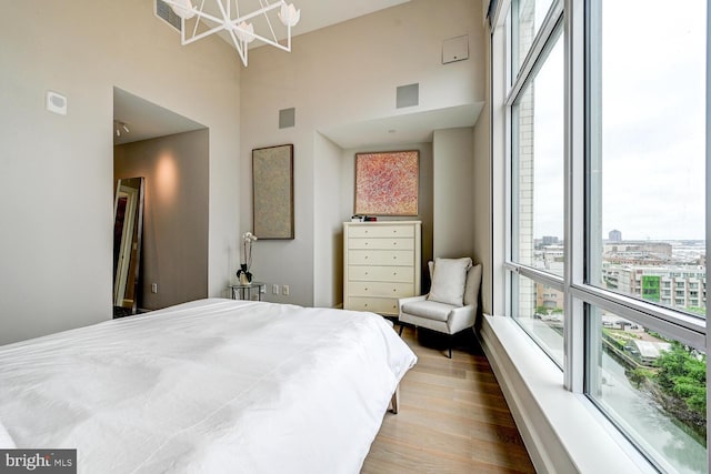 bedroom featuring wood-type flooring and a towering ceiling