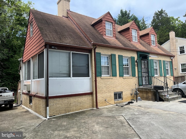 view of front of house with brick siding and a chimney