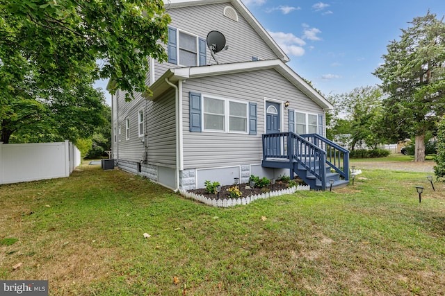 view of front of home with cooling unit and a front lawn