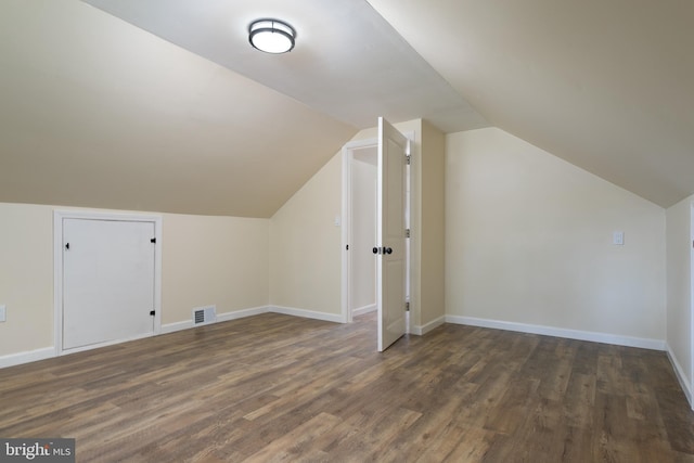 additional living space with lofted ceiling, wood finished floors, visible vents, and baseboards