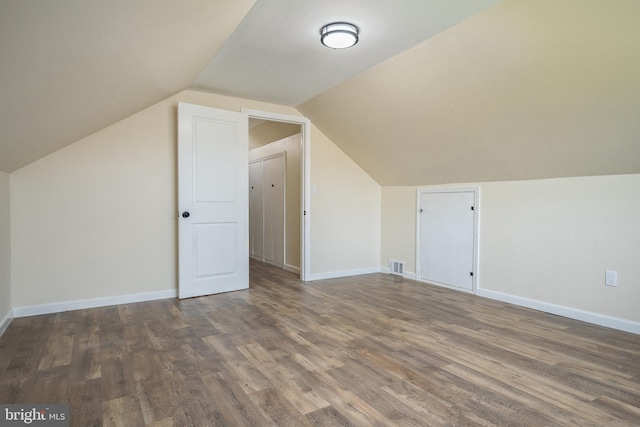 additional living space with lofted ceiling, wood finished floors, visible vents, and baseboards