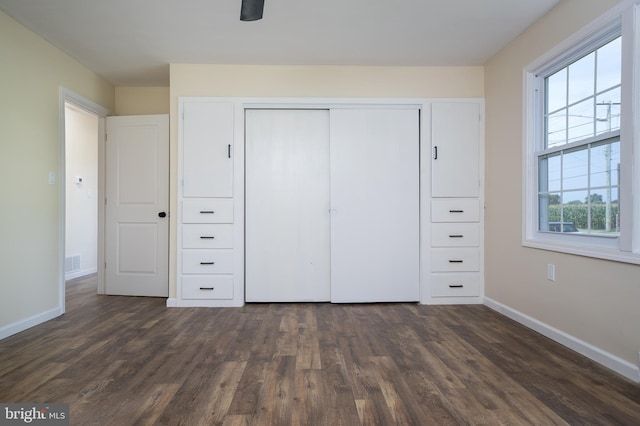 unfurnished bedroom with visible vents, baseboards, a closet, and dark wood-style flooring