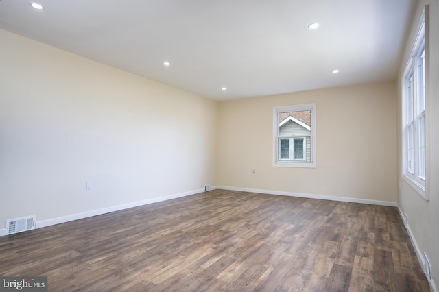 spare room featuring visible vents, recessed lighting, baseboards, and dark wood-style flooring