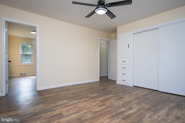 unfurnished bedroom with wood finished floors, visible vents, a closet, and baseboards