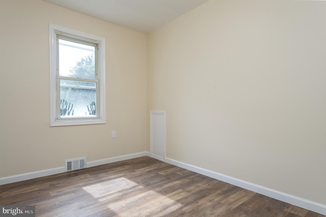 empty room featuring visible vents, baseboards, and dark wood-style flooring