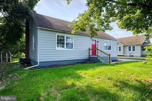 view of front of home with a front yard and central AC