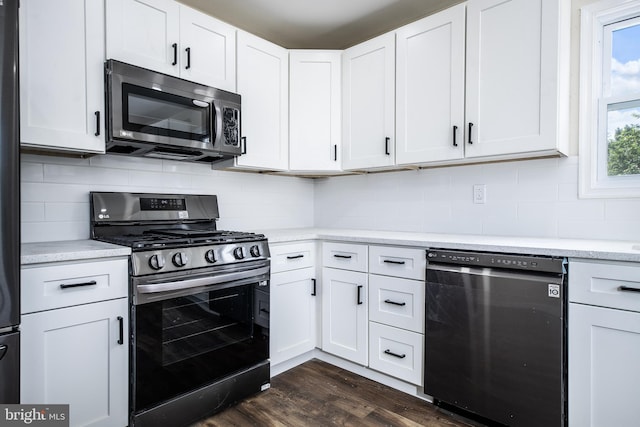 kitchen with dark wood-type flooring, white cabinetry, appliances with stainless steel finishes, light countertops, and decorative backsplash