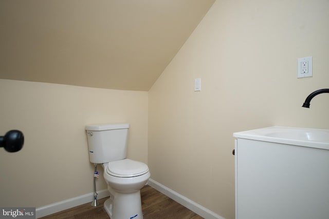 half bathroom featuring vaulted ceiling, toilet, wood finished floors, and baseboards