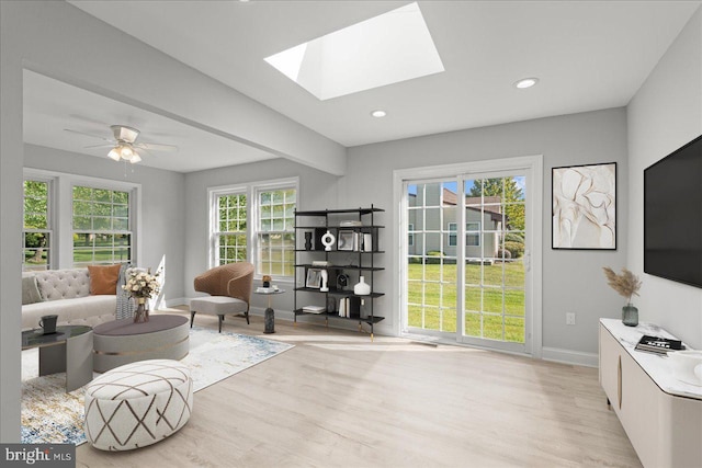 living area with baseboards, beam ceiling, recessed lighting, light wood-style flooring, and a skylight