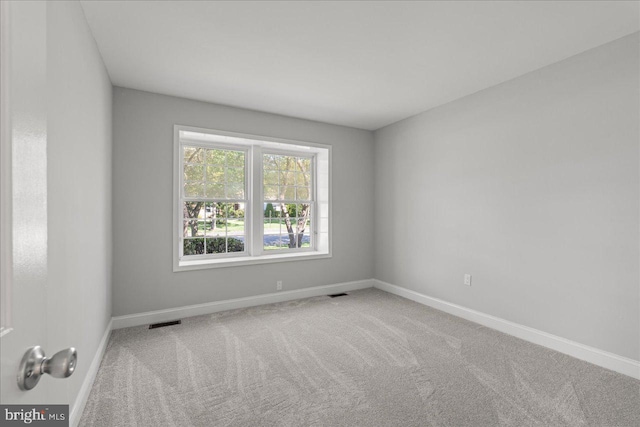 spare room with carpet, visible vents, and baseboards