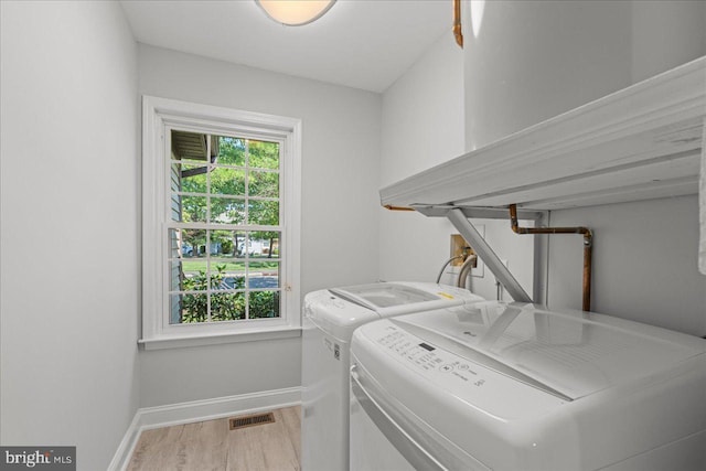 clothes washing area featuring laundry area, plenty of natural light, visible vents, and washer and clothes dryer