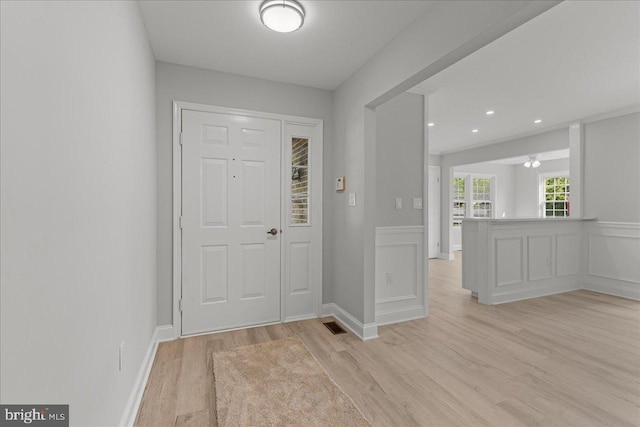 entryway featuring a decorative wall, light wood-style floors, and wainscoting