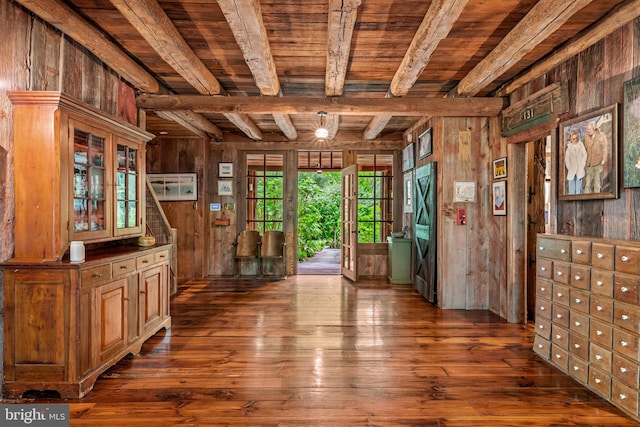 interior space with wood ceiling, beamed ceiling, wooden walls, and dark hardwood / wood-style floors