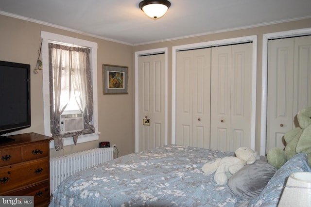 bedroom with radiator heating unit, ornamental molding, two closets, and cooling unit