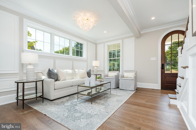 living room with hardwood / wood-style flooring, ornamental molding, a notable chandelier, and a healthy amount of sunlight